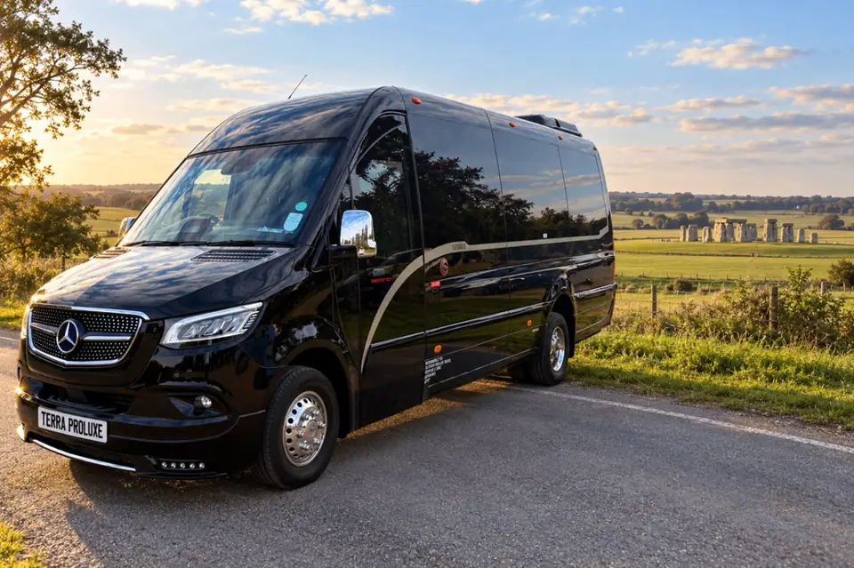 Black Mercedes-Benz Sprinter on a country road with standing stones in the distance.