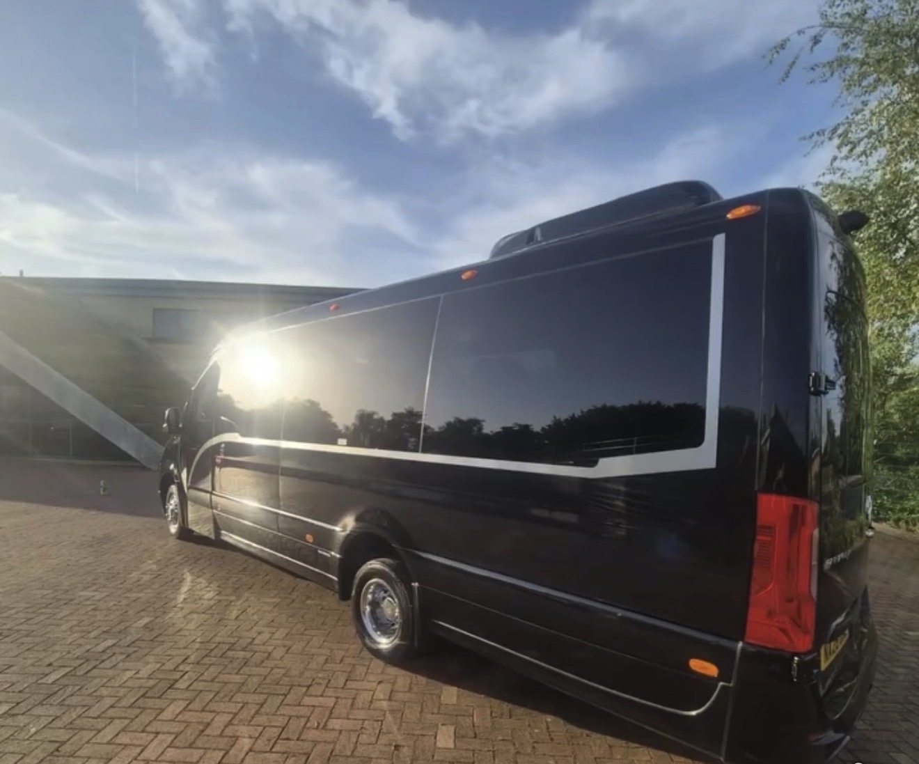 Side profile of the black executive Sprinter minibus with tinted privacy glass